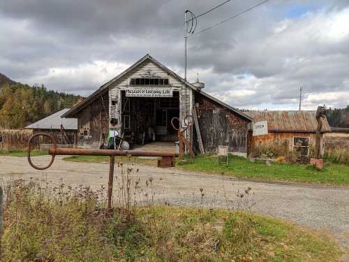 A rustic barn with a sign reading "Museum of Country Life," surrounded by fields and cloudy skies.