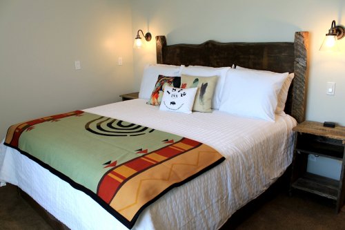 Cozy bedroom featuring a large bed with decorative pillows and a patterned blanket, set against a neutral wall.