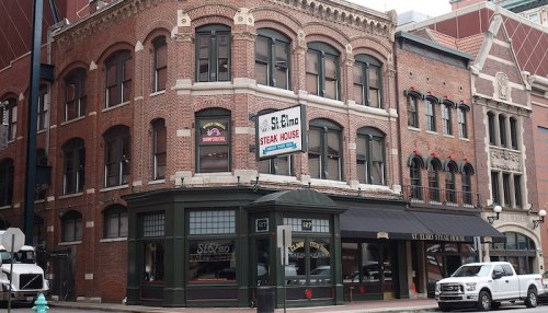 Historic brick building featuring St. Elmo Steak House sign, with large windows and a classic architectural style.