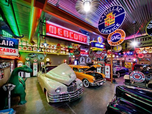 A vibrant vintage car museum filled with classic cars, neon signs, and retro gas station memorabilia.