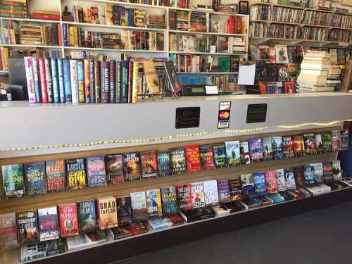 A cozy bookstore interior with shelves of books, a display counter, and a variety of titles on the lower shelf.