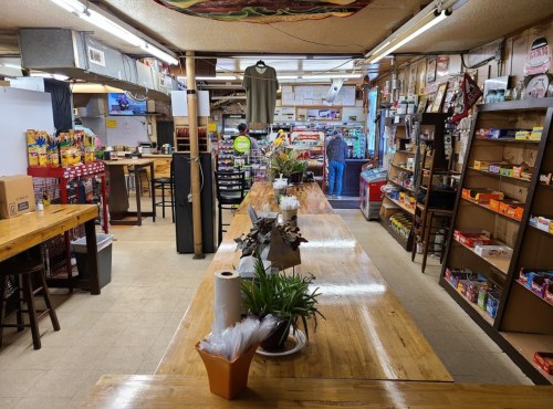A cozy convenience store interior with wooden counters, shelves stocked with snacks, and a welcoming atmosphere.