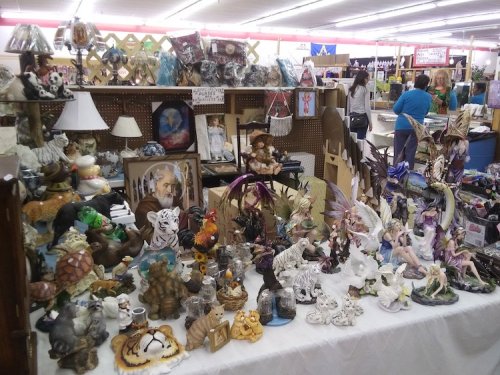 A vibrant display of various decorative figurines and collectibles on a table at a market or fair.