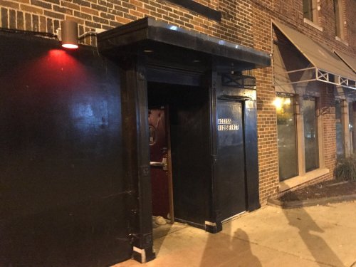 A dimly lit entrance to a building with a black door and a sign that reads "ACCESS LEADS HERE."