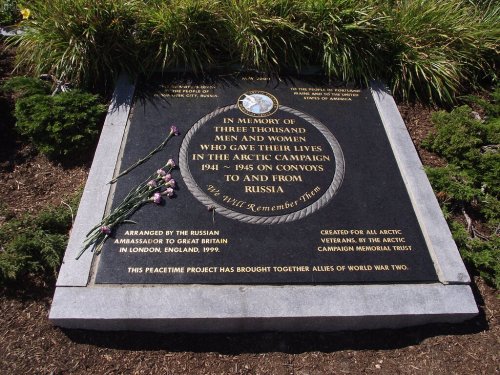 Memorial plaque honoring 3,000 individuals who served in the Arctic Campaign during World War II, with flowers laid beside it.