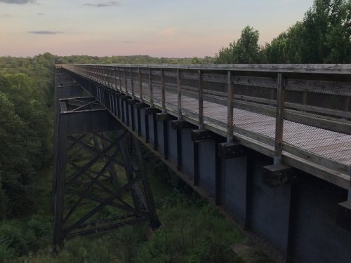 A long, elevated bridge spans a lush green landscape under a soft evening sky.