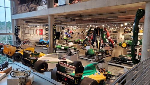 A spacious automotive museum displaying various vintage race cars and motorcycles, with a focus on Lotus vehicles.