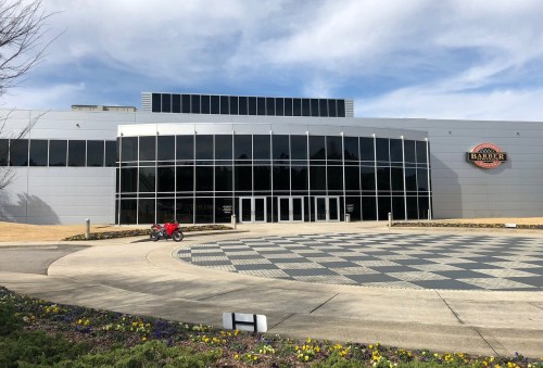 Modern building with large glass windows, a checkered pavement, and a motorcycle parked outside.