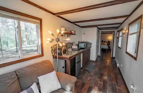 Cozy interior of a small cabin featuring a living area, kitchenette, and hallway leading to a bedroom.