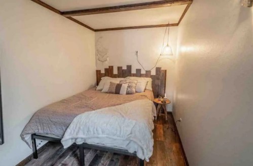 Cozy bedroom with a wooden bed frame, soft bedding, and a small bedside table in a minimalist setting.