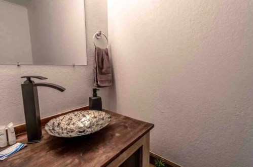 A modern bathroom sink with a decorative bowl, sleek faucet, and a towel hanging on the wall.