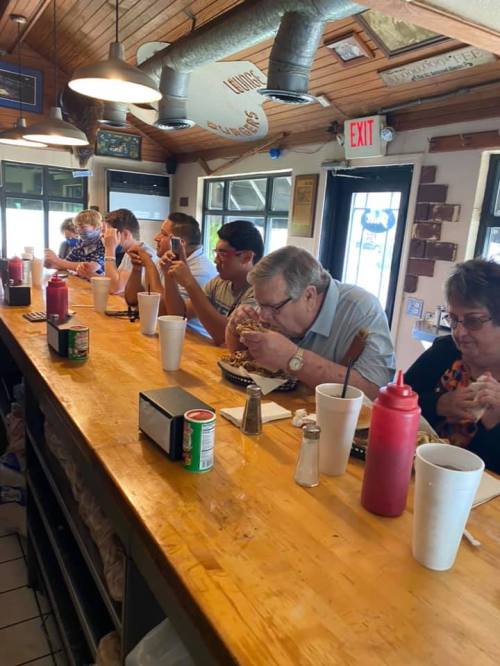 A group of people sitting at a counter, enjoying meals and drinks in a casual diner setting.