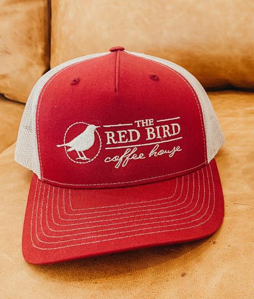 A red and white trucker hat featuring "The Red Bird Coffee House" logo with a bird graphic.
