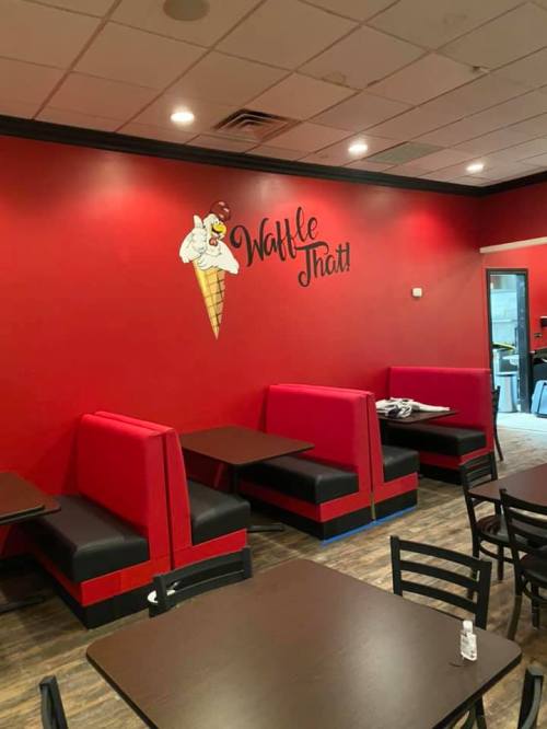 Interior of a red-walled ice cream shop with booth seating and a playful ice cream cone mural.