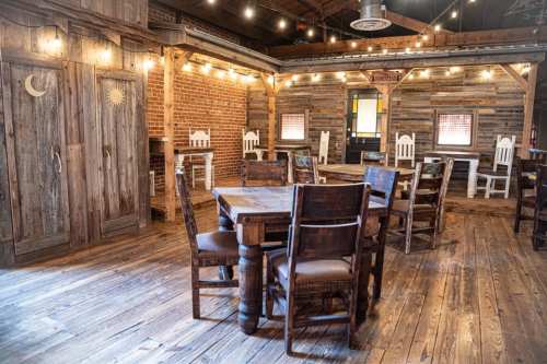 Cozy rustic interior with wooden tables and chairs, warm lighting, and exposed brick walls.