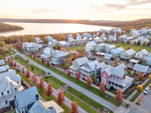 Aerial view of a suburban neighborhood with colorful autumn trees and a lake in the background during sunset.