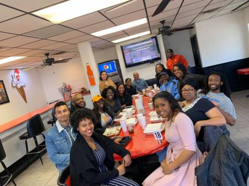 A group of diverse people gathered around a table in a restaurant, enjoying a meal and socializing.