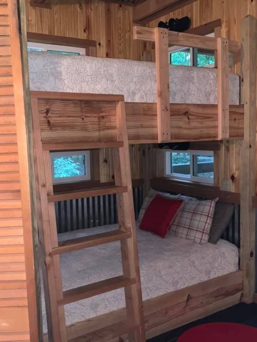 Cozy wooden bunk beds in a rustic room with natural light and decorative pillows.