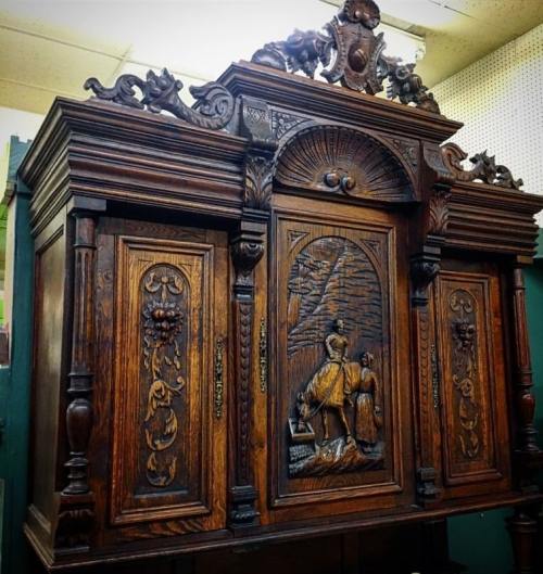 Intricately carved wooden cabinet with ornate details and a central relief depicting a figure on horseback.