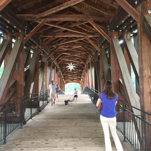 A wooden bridge with a star decoration, featuring people walking, including a woman with a dog.