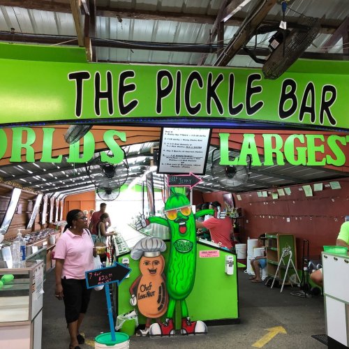A vibrant pickle bar with a large sign reading "World's Largest Pickle Bar," featuring a cartoon pickle character.