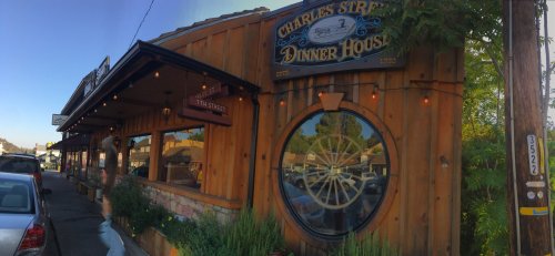 Exterior of Charles Street Dinner House, featuring wooden architecture and a large circular window, with parked cars nearby.