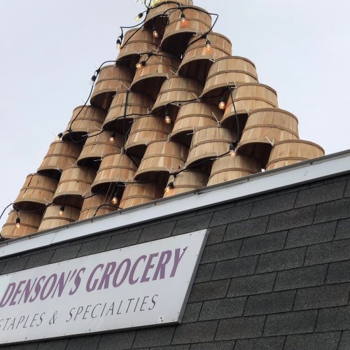 A pyramid of wooden baskets topped with string lights on the roof of Denson's Grocery store.