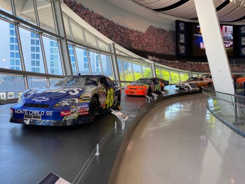 A display of classic race cars in a modern museum setting, featuring various colorful designs and sponsor logos.