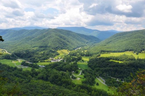 A panoramic view of lush green mountains and valleys under a partly cloudy sky.