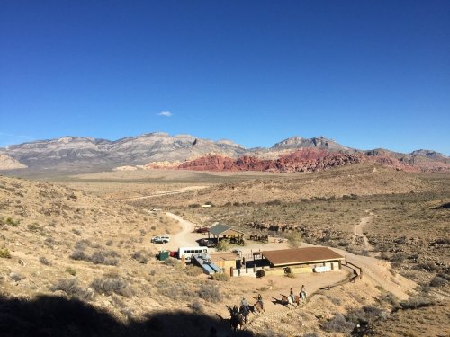 A scenic view of a desert landscape with mountains, a small settlement, and a clear blue sky.