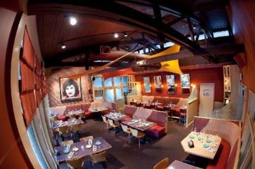 Interior of a modern restaurant featuring colorful decor, booths, and tables set for dining.