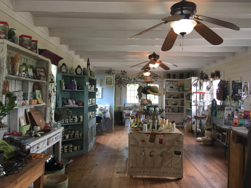 A cozy shop interior with wooden floors, shelves of products, and ceiling fans, creating a warm, inviting atmosphere.