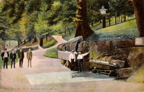 A vintage postcard of Rock Springs Park, W.Va., featuring a scenic path and people near a rock formation.