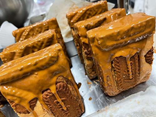Close-up of freshly baked cakes topped with a glossy caramel glaze, arranged neatly on a silver tray.