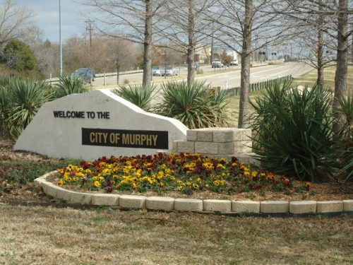 Welcome sign for the City of Murphy, surrounded by colorful flowers and greenery along a roadside.