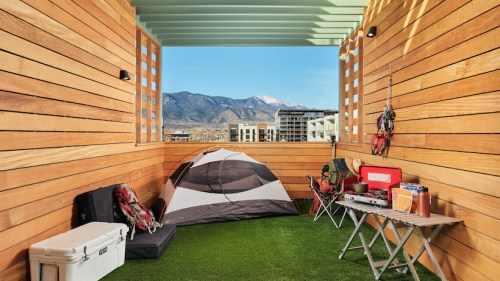 A cozy outdoor space with a tent, camping gear, and a view of mountains in the background.