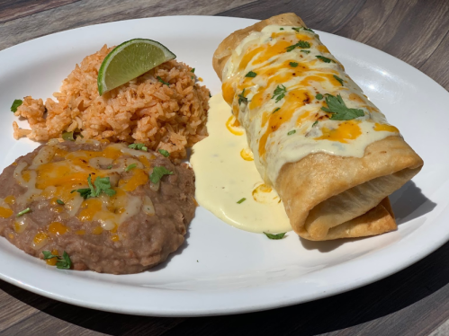A plate featuring two cheesy enchiladas, rice, and refried beans, garnished with lime and cilantro.