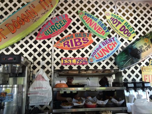 Interior of a casual eatery with signs promoting best burgers, ribs, hot dogs, and lunch specials since 1994.