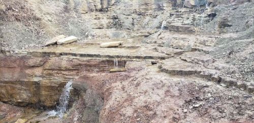 A rocky landscape with small waterfalls cascading over stone ledges in a natural setting.