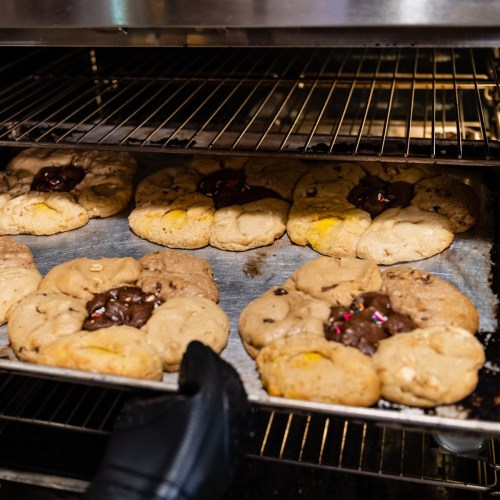 Freshly baked cookies with chocolate centers, cooling on a rack inside an oven.