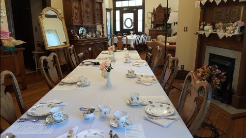 A beautifully set dining table with floral china, silverware, and a vase of flowers in a cozy, elegant room.