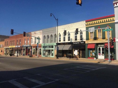A charming street scene featuring colorful storefronts and traffic lights under a clear blue sky.