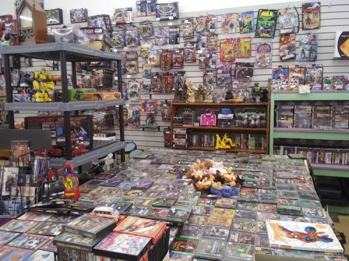 A vibrant store interior filled with shelves of toys, games, and collectibles, with a table covered in DVDs and plush toys.