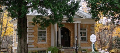 A charming brick library building surrounded by trees and autumn foliage.
