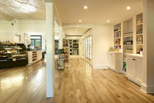 Bright, modern store interior with wooden floors, shelves of products, and a display case in the background.