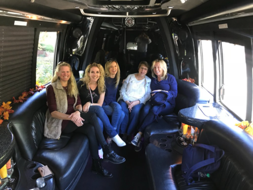 Five women sitting together in a stylish black limousine, smiling and enjoying their time.