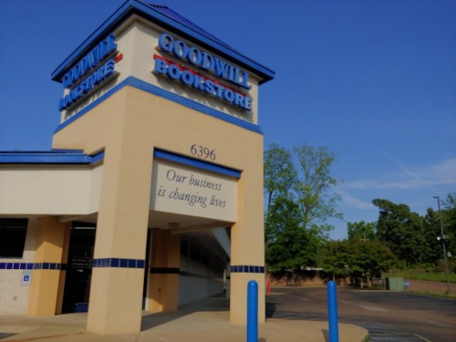 Exterior of a Goodwill Bookstore with a blue sky, featuring a sign that reads "Our business is changing lives."