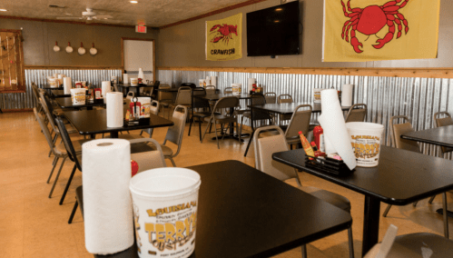 Interior of a casual dining restaurant with empty tables, condiments, and crab-themed decor on the walls.