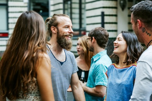 A group of friends laughing and chatting outdoors, enjoying a lively social gathering.