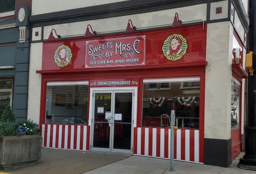 Exterior of "Sweets by Mrs. C," an ice cream shop with a red and white striped facade and cheerful signage.